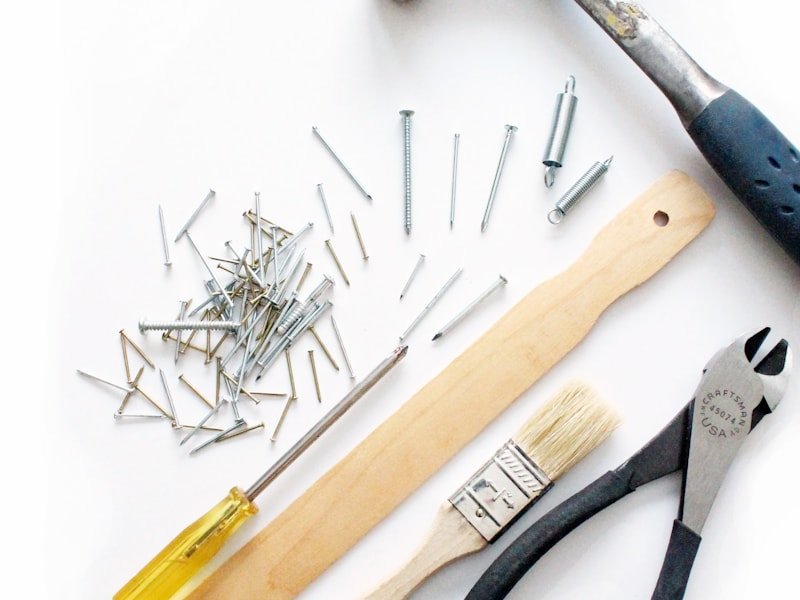 Flat-lay of screws, fasteners, and assembly tools including screwdriver and hammer.